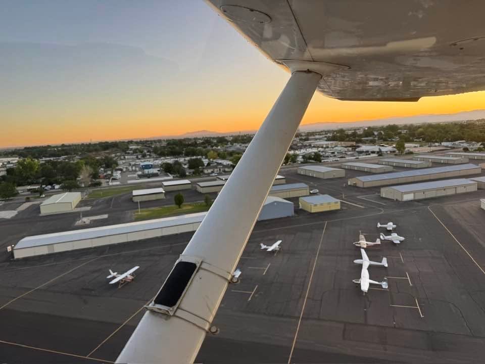 Wing strut over the airport at sunset